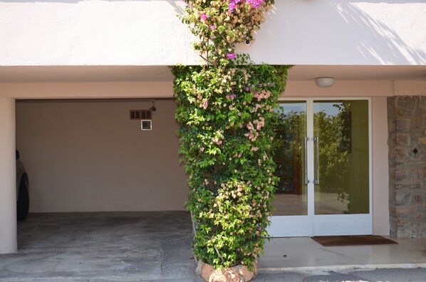 A building with a garage door, a stone wall, and a vertical garden with flowers. - Ste Maxime, sea view Comfortable, quiet, walk to the town center and beaches (Sainte-Maxime)