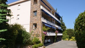 A two-story building with a stone facade, a balcony with blue awnings, and a parked vehicle in front. - Ste Maxime, sea view Comfortable, quiet, walk to the town center and beaches (Sainte-Maxime)