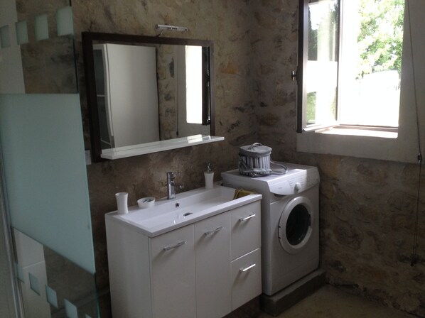 A bathroom with a white sink, mirror, and a washing machine. - Stone house with Jacuzzi and air conditioning (Vallon-Pont-D'arc)