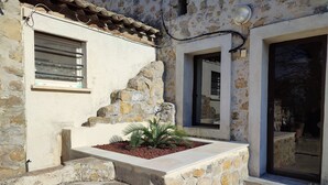 A stone building with a small garden, a window, and a door leading to an outdoor area. - Stone house with Jacuzzi and air conditioning (Vallon-Pont-D'arc)