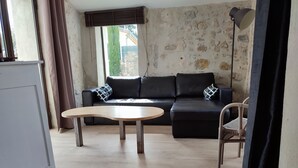 A living room with a sofa, a coffee table, and a chair. - Stone house with Jacuzzi and air conditioning (Vallon-Pont-D'arc)