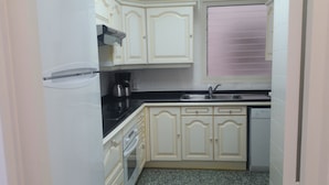 A compact kitchen with white cabinets, a black countertop, a built-in oven, and a dishwasher. - ROSES: Super Apartment on the FIRST LINE OF THE SEA for 6–8 PEOPLE in the CITY CENTER (ROSAS)