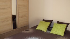 Une chambre à coucher avec un lit, deux oreillers, une armoire en bois et un tableau accroché au mur.