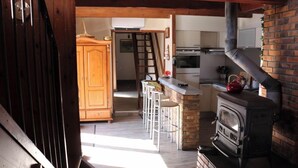 A kitchen with a brick stove, wooden cabinets, and a bar area with stools. - Great Pyrenees typical barn furnished with all modern comforts (Cadeilhan-Trachère)