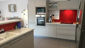 A modern kitchen with a built-in oven, a coffee maker, and a red backsplash.