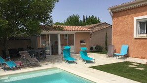 A swimming pool with lounge chairs, a patio area, and a building with a tiled roof.