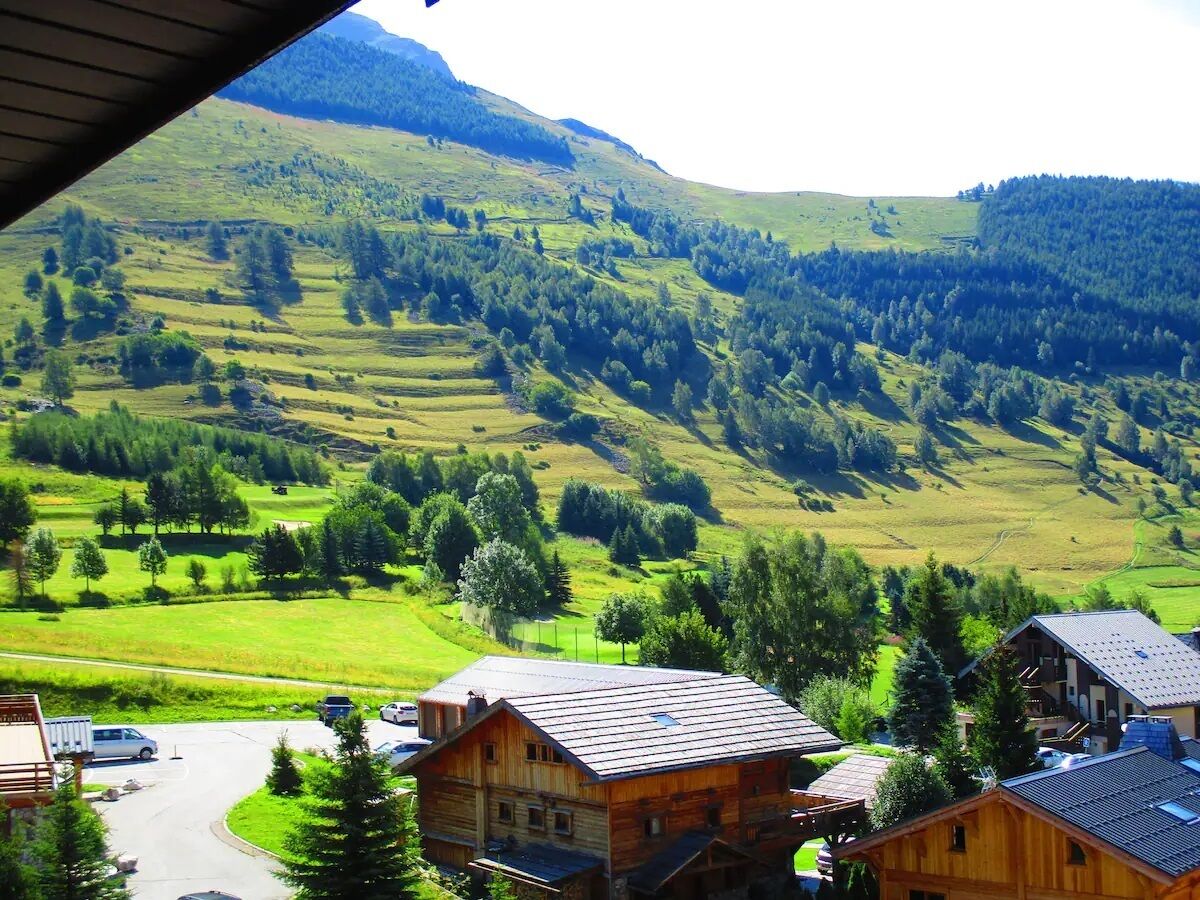 Un paysage rural avec des maisons en bois, une route et une montagne en arrière-plan.
