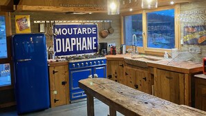 Eine rustikale Küche mit Holzausstattung, einem blauen Kühlschrank und einem Schild mit der Aufschrift 'MOUTARDE DIAPHANE'.