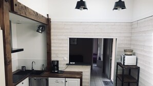A compact kitchen with a dishwasher, coffee maker, and a microwave on a small table.