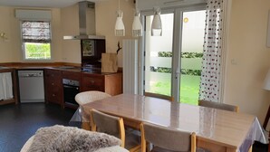 Une cuisine équipée d’une table à manger, de chaises, d’un lave-vaisselle et d’un réfrigérateur.