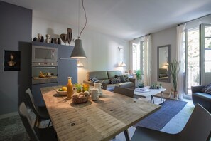 A modern kitchen with a dining area, a sofa, and a large window. - APARTMENTS AND LOFTS ST REMY DE PROVENCE (Saint-Rémy-De-Provence)