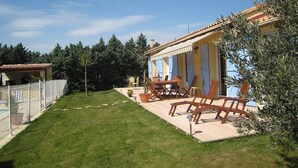 Eine Villa mit Terrasse, Sitzgelegenheiten im Freien und einem Pool.