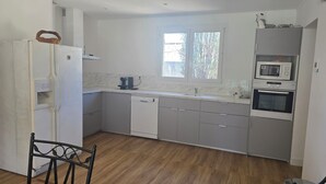 Eine Küche mit Geschirrspüler, Mikrowelle, Backofen und einem Fenster mit Blick auf Bäume.