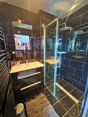Een bad/douchecombinatie, een bubbelbad, een haardroger, handdoeken