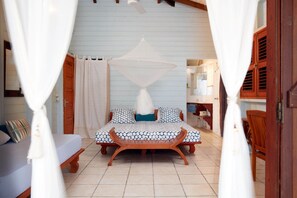 Ein Schlafzimmer mit Bett, Vorhängen und einer hölzernen Bank.