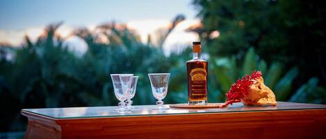A wooden table with a bottle of liquor, two glasses, and a decorative item.