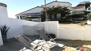 Eine Holzterrasse mit zwei Liegestühlen und einem Sandkasten.