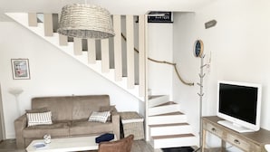 Ein modernes Wohnzimmer mit Treppe, Sofa, Couchtisch, Fernseher und Sessel.