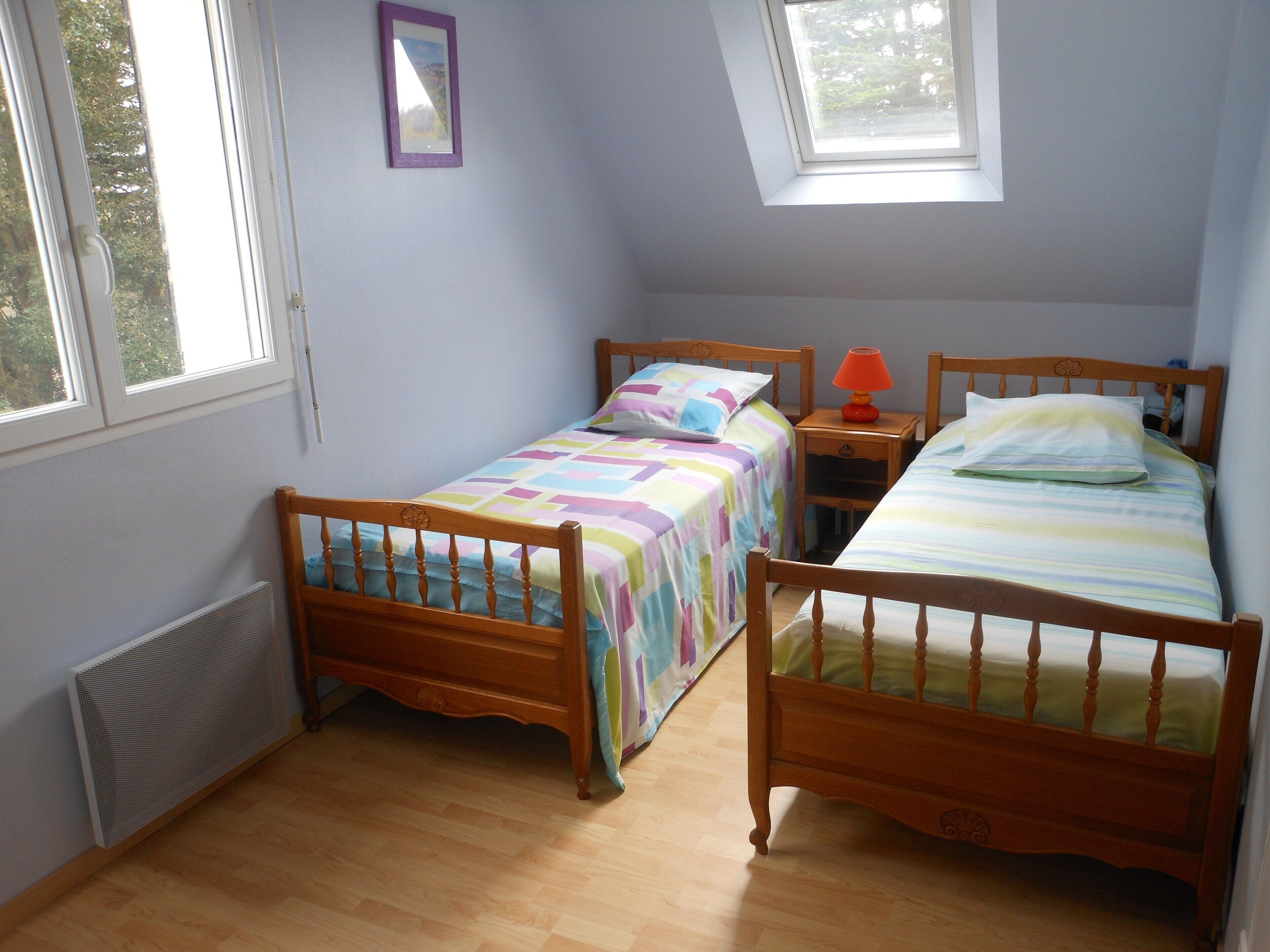 Un dormitorio con dos camas de madera, una ventana y un radiador.