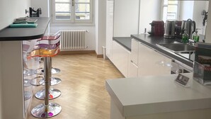 Una cocina moderna con armarios blancos, una isla central y un ventanal que proporciona luz natural.