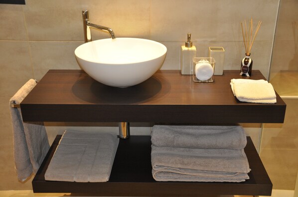A bathroom with a large white vessel sink, a dark wooden vanity, and neatly folded towels. - Charming Como - In the old town (Como)