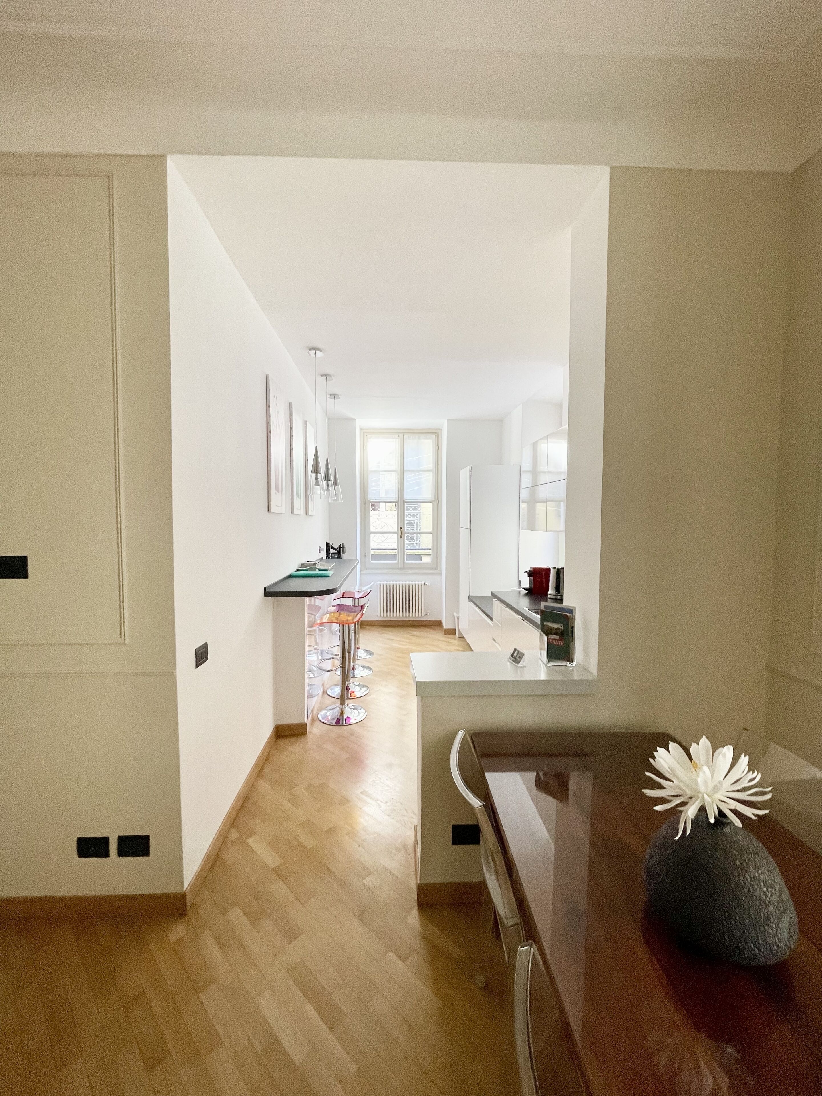 A modern kitchen with a central island, a dining area with a table and chairs, and a view of the living room through an open doorway.