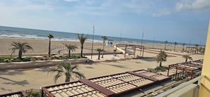 A beachside promenade with palm trees, a boardwalk, and a view of the ocean.