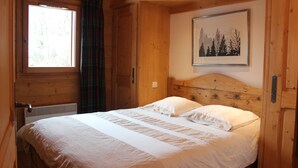 A wooden cabin bedroom with a bed, a window, and a framed picture on the wall. - Superb 70M2 apartment, fireplace, terrace, pool/spa and private shuttle service  (Champagny-En-Vanoise)