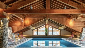 An indoor swimming pool with a high wooden ceiling and stone pillars. - Superb 70M2 apartment, fireplace, terrace, pool/spa and private shuttle service  (Champagny-En-Vanoise)