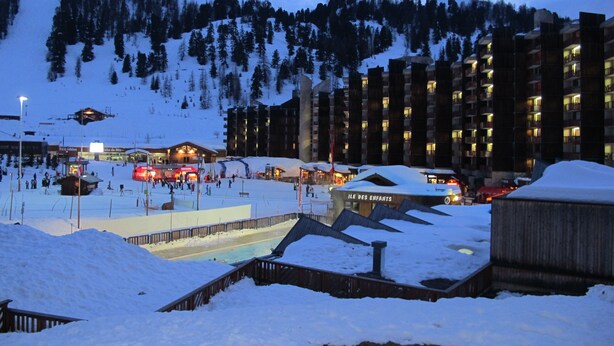 Une station de ski comprenant plusieurs bâtiments, dont un hôtel doté de balcons et d’un espace piscine.
