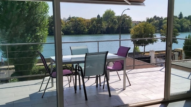 A modern outdoor patio with a table and chairs, overlooking a lake. - Charming cottage by the Seine (Villeneuve-le-Roi)