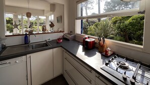 A modern kitchen with a Bosch dishwasher, a gas stove, and a large window offering a view of greenery.
