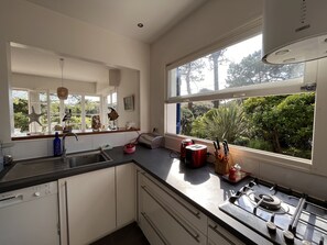 A modern kitchen with a Bosch dishwasher, a gas stove, and a large window offering a view of greenery.