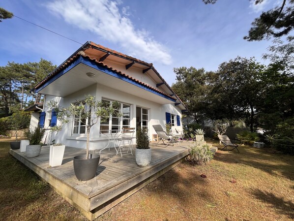 A two-story house with a wooden deck, large windows, and a tiled roof.