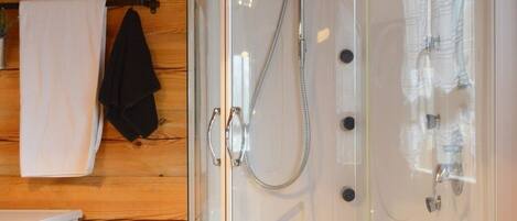 A modern bathroom with a glass-enclosed shower, a white sink, and a washing machine.