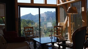 A room with a large window offering a mountain view, wooden furniture, and a table with books. - Architect house in Provence (La Roque-Alric)