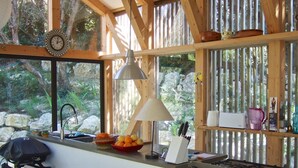 A kitchen with a wooden interior, a sink, a stove, and a window overlooking a garden. - Architect house in Provence (La Roque-Alric)
