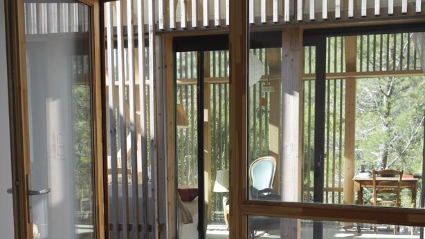 A bedroom with a bed, a sliding glass door leading to an outdoor area with a table and chairs. - Architect house in Provence (La Roque-Alric)