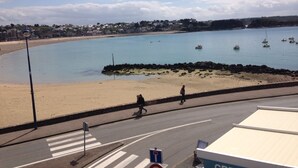 A coastal road with a pedestrian crossing leading to a sandy beach.
