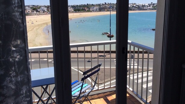 A balcony with a view of a beach and the sea.