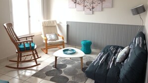 A living room with a rocking chair, a sofa, a coffee table, and a wall art piece.