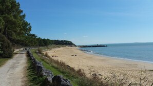 A coastal road leading to a sandy beach with a clear view of the sea and a rocky outcrop in the distance. - Bright and comfortable 3-room house in Saint-Palais, facing the sea (Saint-Palais-Sur-Mer)
