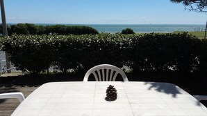 A table with a pine cone centerpiece, white chairs, and a view of the sea. - Bright and comfortable 3-room house in Saint-Palais, facing the sea (Saint-Palais-Sur-Mer)