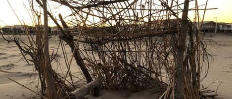 Een constructie van takken en hout op een zandstrand.