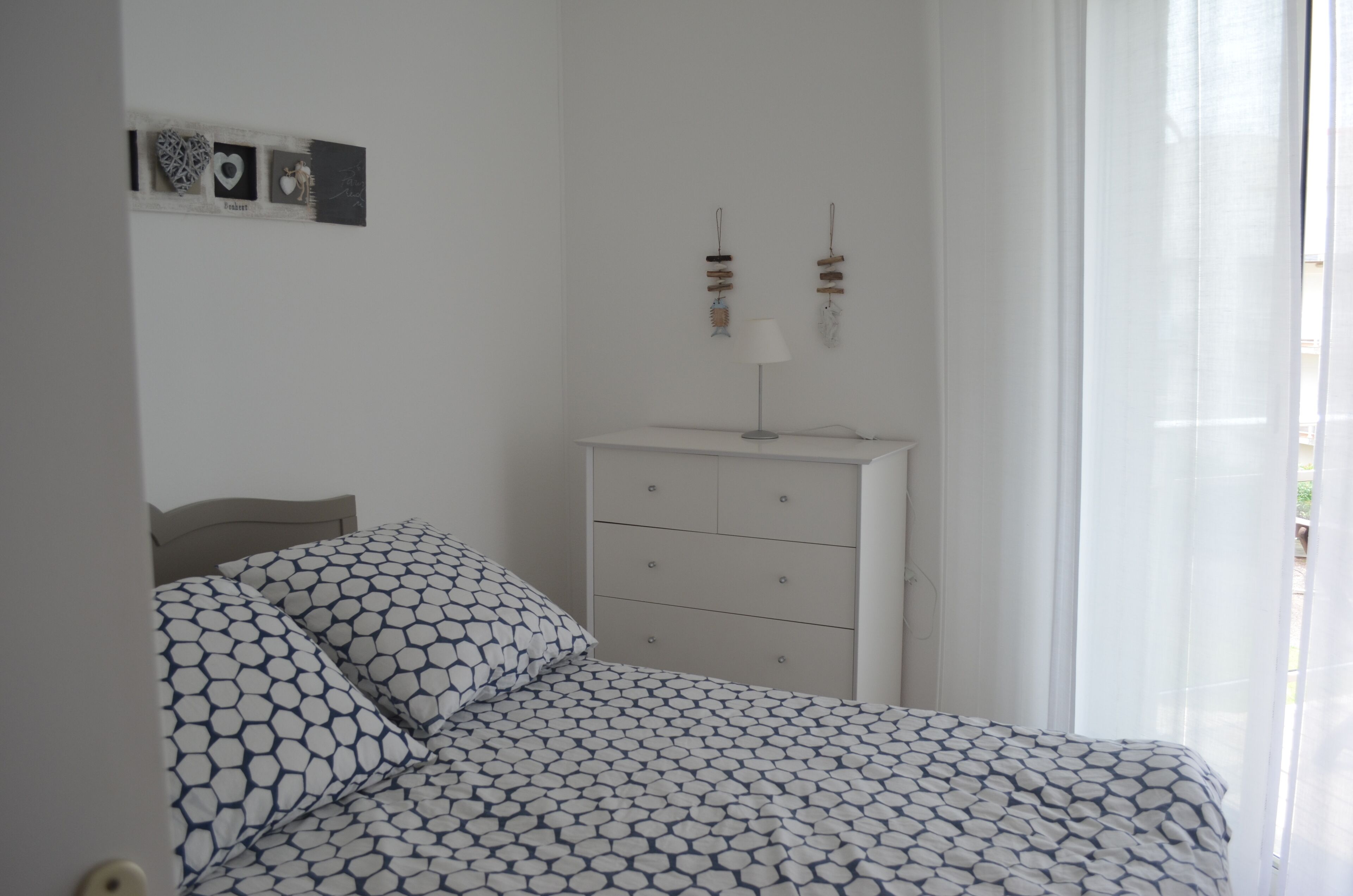 Quarto com cama, penteadeira e um objeto decorativo na parede.