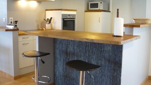 A modern kitchen with a wooden countertop, two bar stools, a microwave, and a built-in oven. - Single storey house, enclosed land 400 m from the beach of pors-Carn (Penmarch)