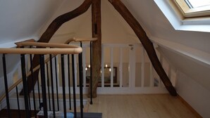 Un escalier en bois avec une rampe blanche et une lucarne au-dessus.