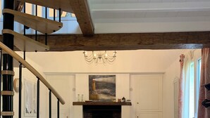 Un salon spacieux avec une cheminée, un escalier et un lustre.