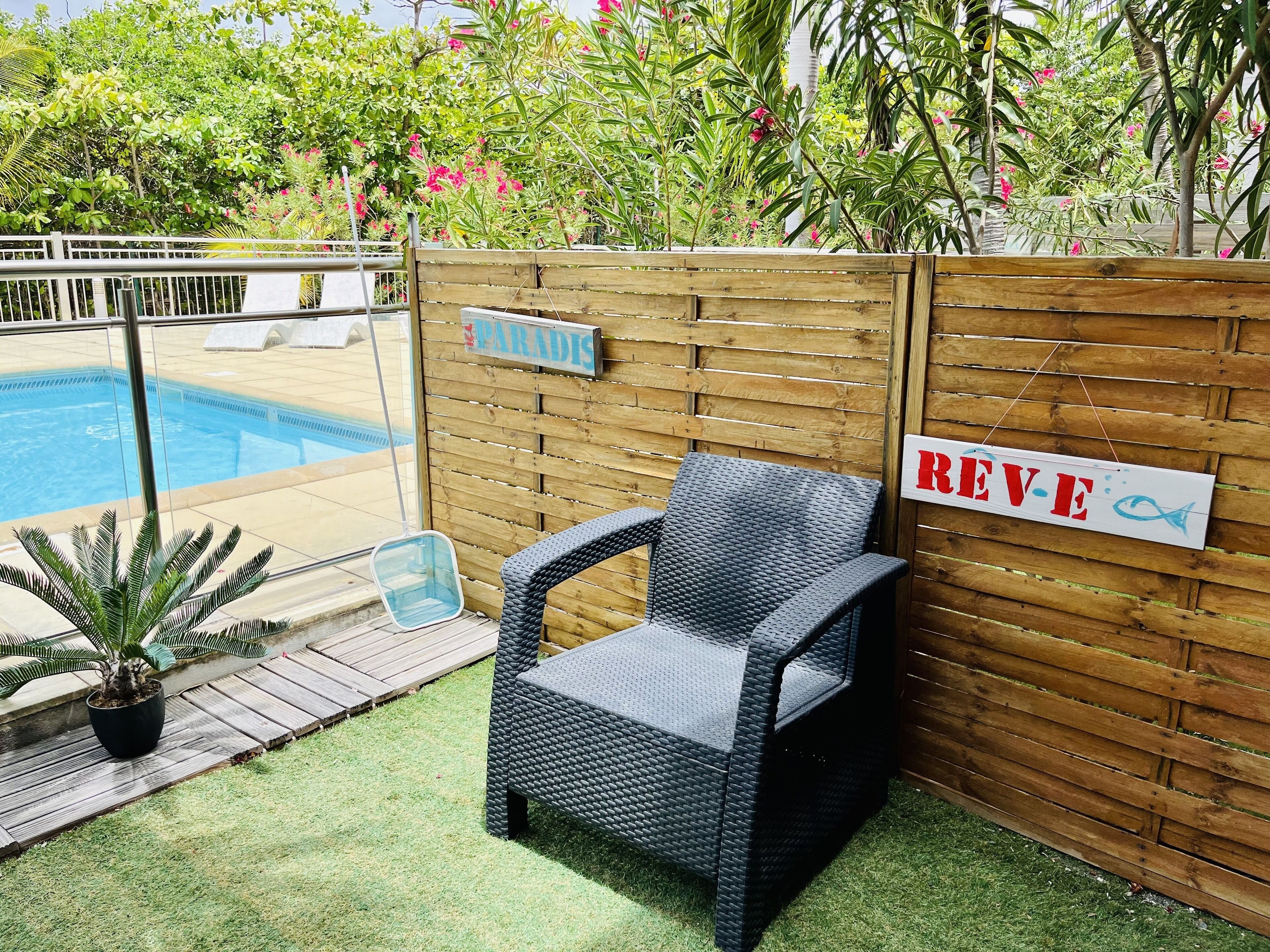 A wicker chair near a wooden fence with a sign that reads "REVE".