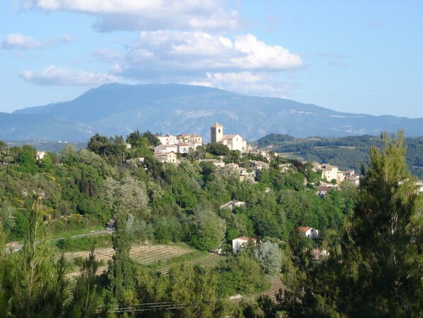 A village with a prominent church on a hill, surrounded by lush greenery and mountains in the background. - Detached house, quiet, beautiful garden, mini pool, Drôme provençale, 2 Pers (Vinsobres)